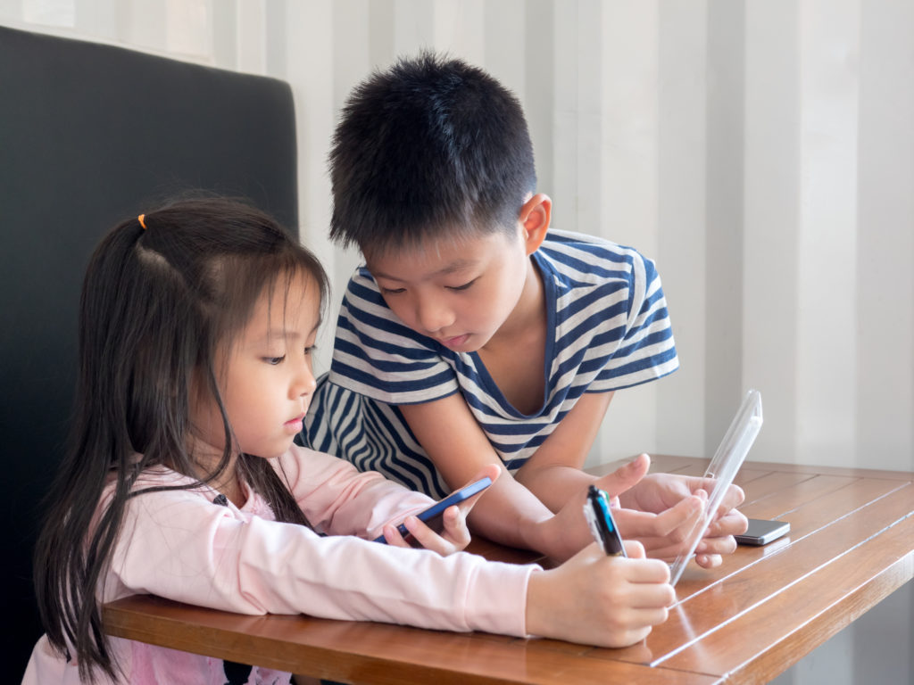 Asia pretty little girl and handsome boy play mobile phone, looking at their phone. Seek opinion from eye doctor.