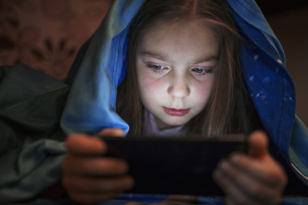child using devices in the dark