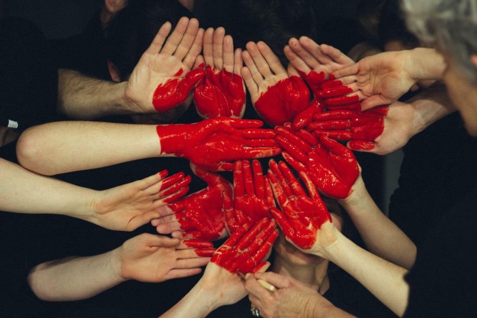 A group of hands with red colour drawing a heart because volunteering in Singapore