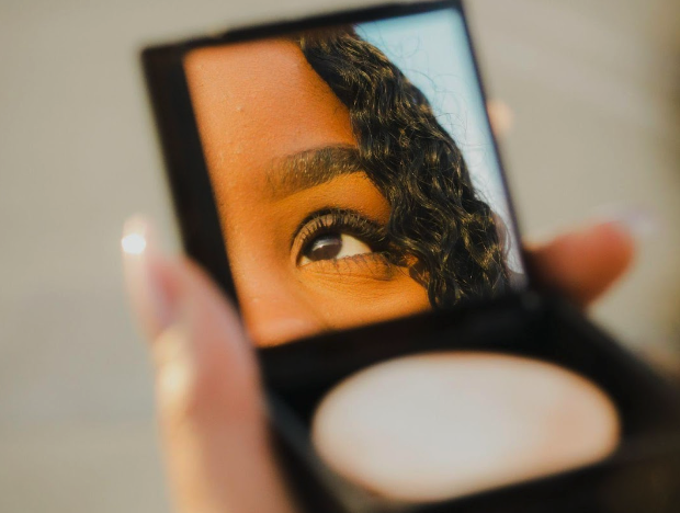 girl in with a small mirror using eye makeup remover for dry eyes