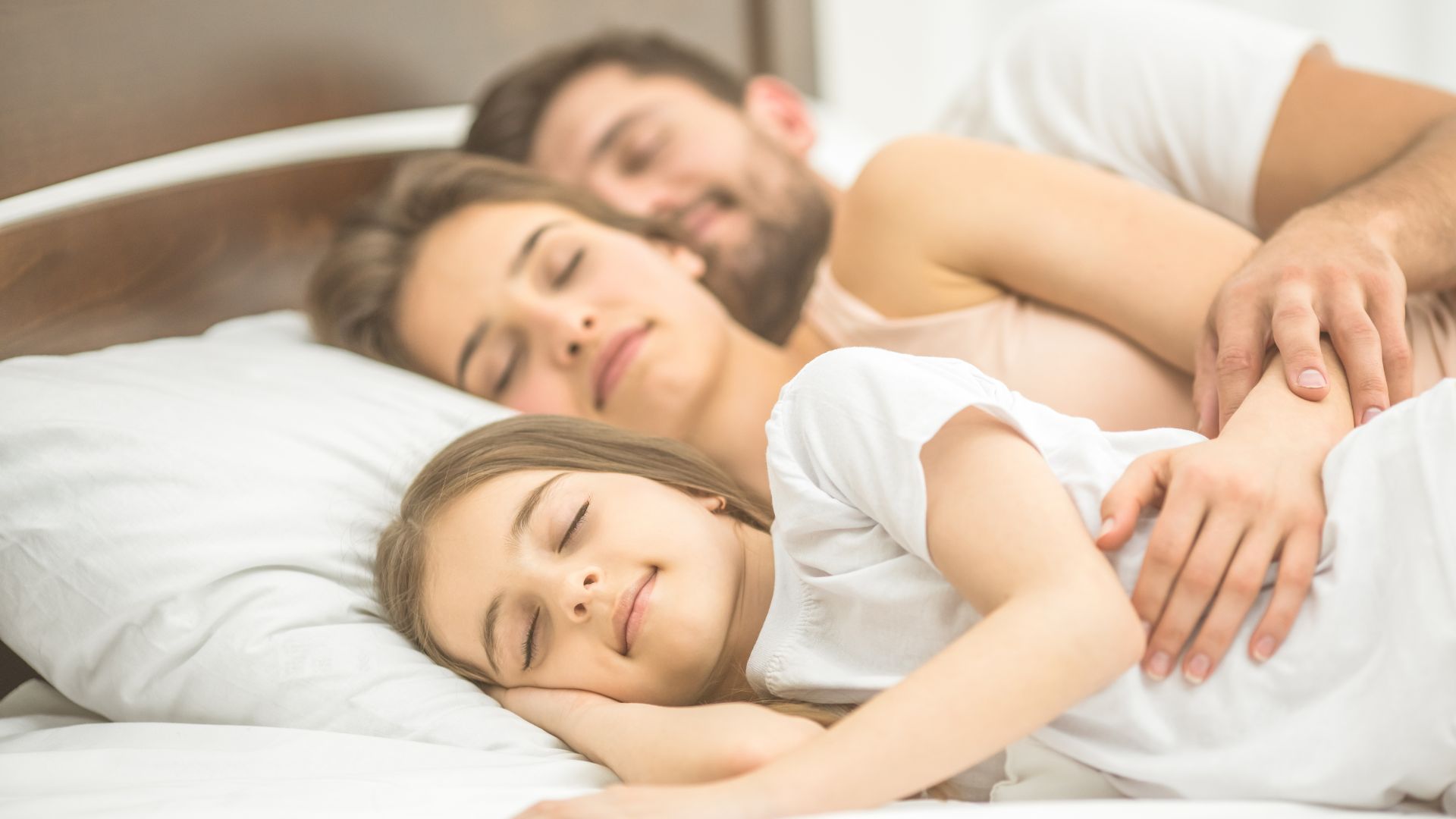 father, mum and daughter sleeping in a bed thanks to the tools that help you sleep better