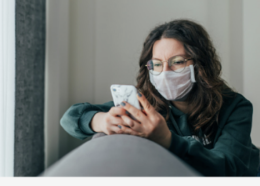 girl with glasses and mask is staring at her smartphone